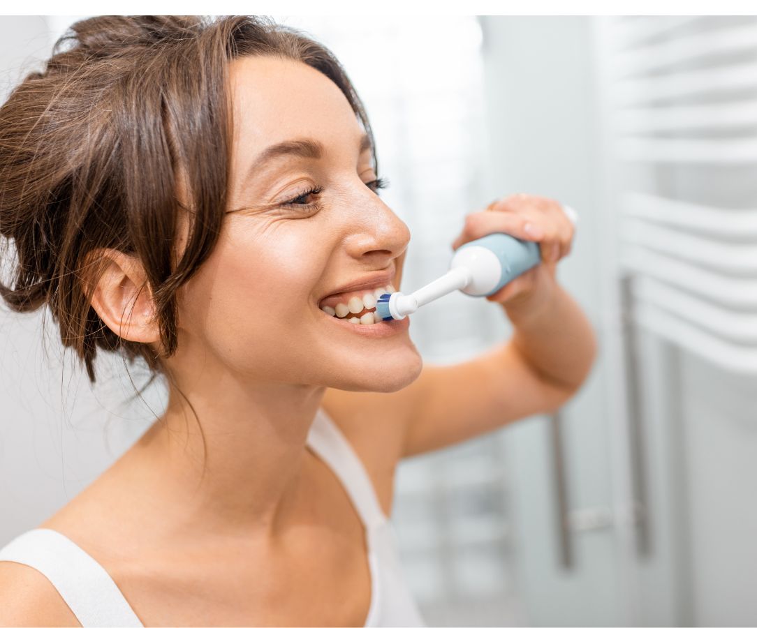 mujer realizandose una mejor higiene dental con su cepillo de dientes electrico